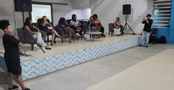 Imagem do palco do Galpão ZL, no qual estão sete pessoas. A foto ilustra o texto sobre o evento 2º Encontro Mulheres na Política: conversa com candidatas a vereadoras.