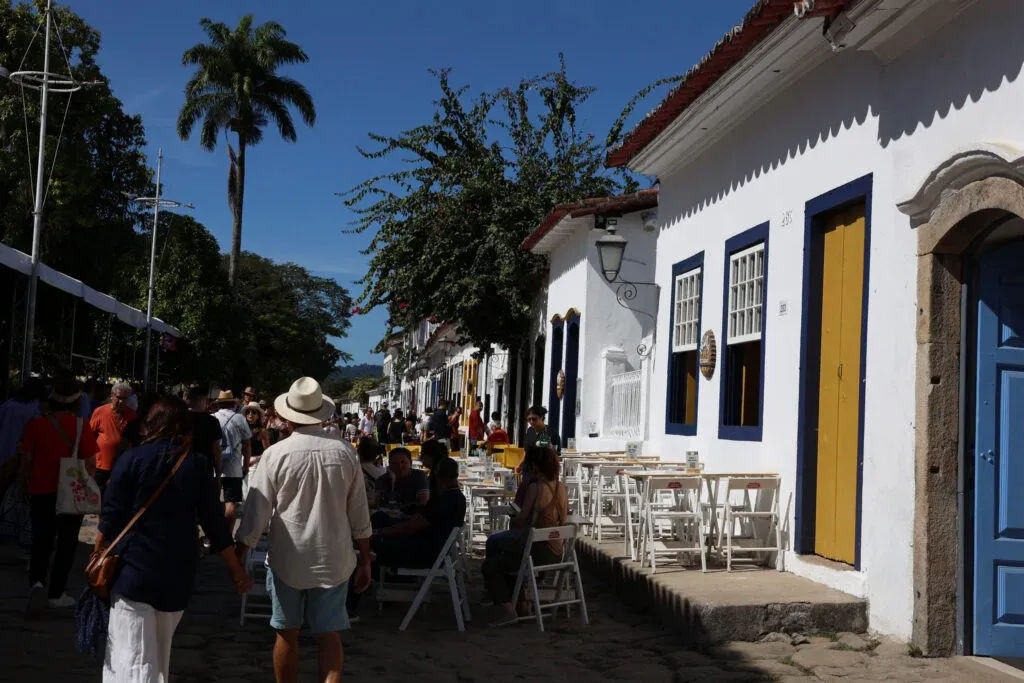 Imagem da 23ª Festa Literária Internacional de Paraty. A foto mostra uma das vias de Paraty (RJ) ocupadas por pessoas, inclusive sentadas em mesas de restaurantes que atendem clientes ao ar livre. A foto ilustra o texto sobre como funciona a Lei Rouanet.