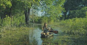 Cena do filme 'Fé que Move Rios'. A imagem mostra uma das pessoas entrevistadas atravessando o rio ao usar um caiaque.