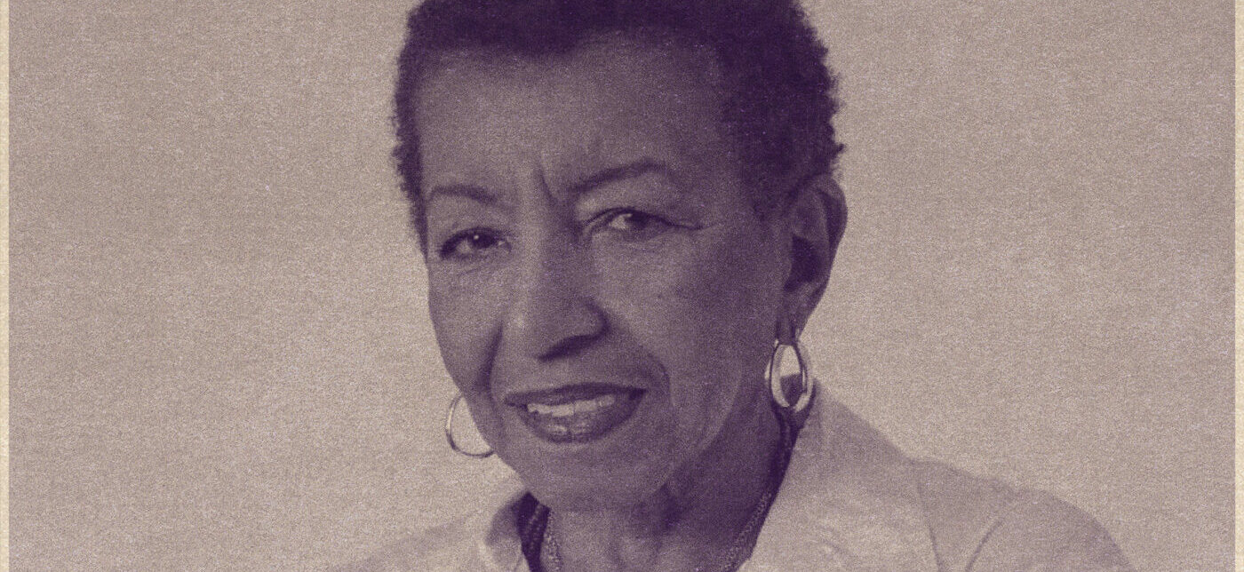 Imagem de divulgação do episódio do podcast 'Escute as Mais Velhas' com Leci Brandão. A foto mostra Leci Brandão. Ela é uma mulher negra com cabelos crespos curtos. Ela aparece sorrindo discretamente e usa um par de brincos.