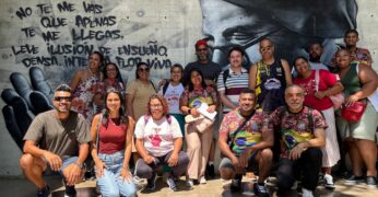 Imagem de pessoas em frente a um mural. Trata-se da comitiva do Jardim Lapena que participou da viagem de imersão a Medellín.