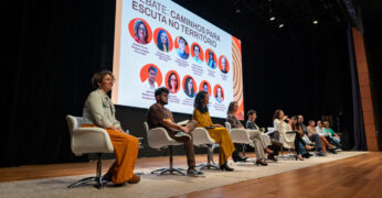 Imagem do palco com as pessoas participantes da segunda mesa do Seminário Territórios Clínicos - Segunda Edição. Elas estão no palco e à frente de uma tela projetada com as fotos delas.