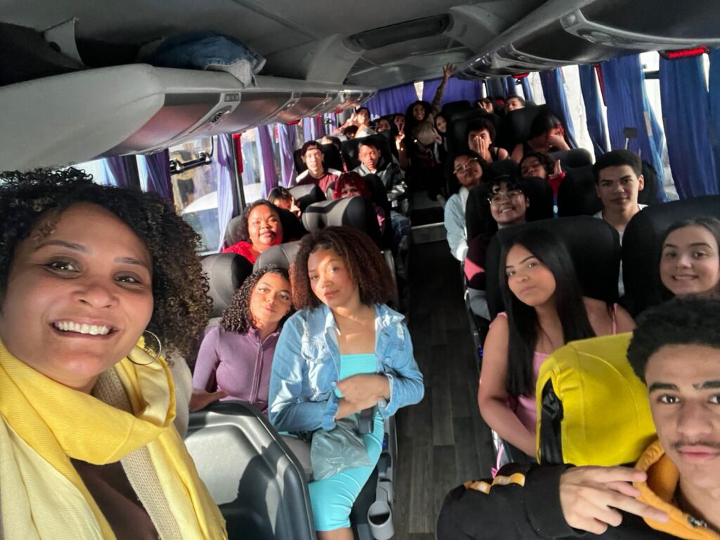 Imagem de passeio realizado por participantes do Projeto Asas + Espaço Jovem. As pessoas estão dentro de um ônibus de turismo e fazem poses para a foto.