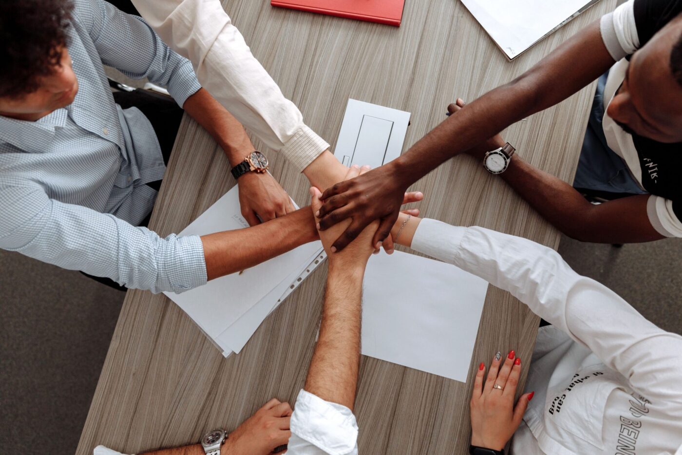 Imagem de pessoas de perfis étnico-raciais diversos sobrepondo suas mãos sobre as outras para representar um gesto de união e solidariedade. A foto ilustra o artigo sobre o Censo interno da Fundação Tide Setubal.