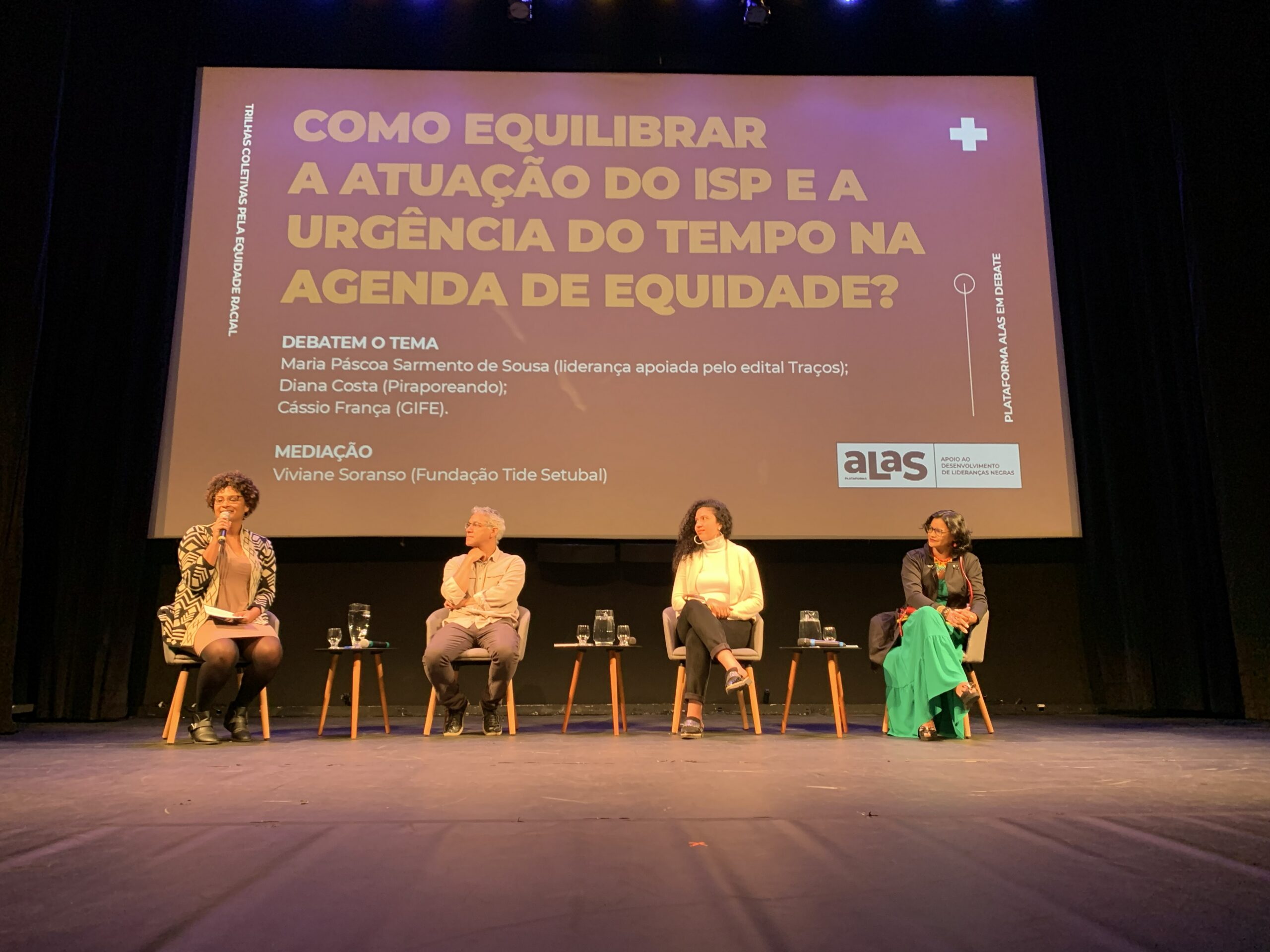 Imagem da edição 2023 do evento Plataforma Alas em Debate. Há quatro pessoas no palco. A foto ilustra o texto sobre busca pela equidade racial.